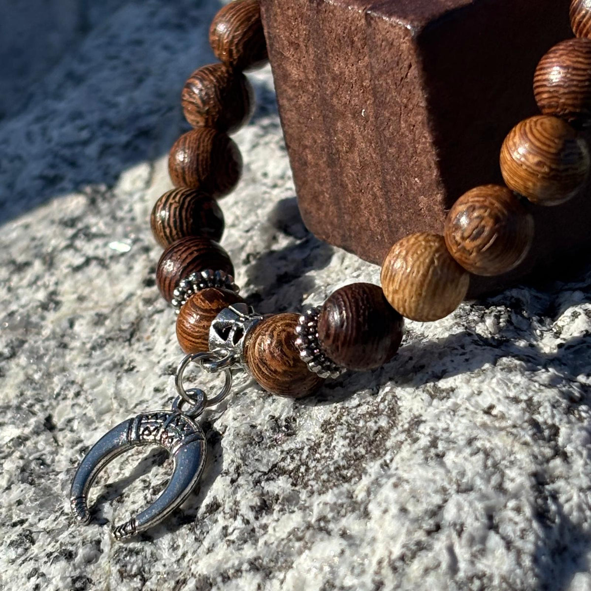 Vue de près d'un bracelet en perles artisanal avec une breloque lune argentée et des perles en bois sur élastique