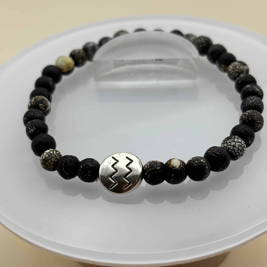 Un beau bracelet en perles sur élastique avec perles en porcelaine et en verre et médaillon avec le signe du verseau