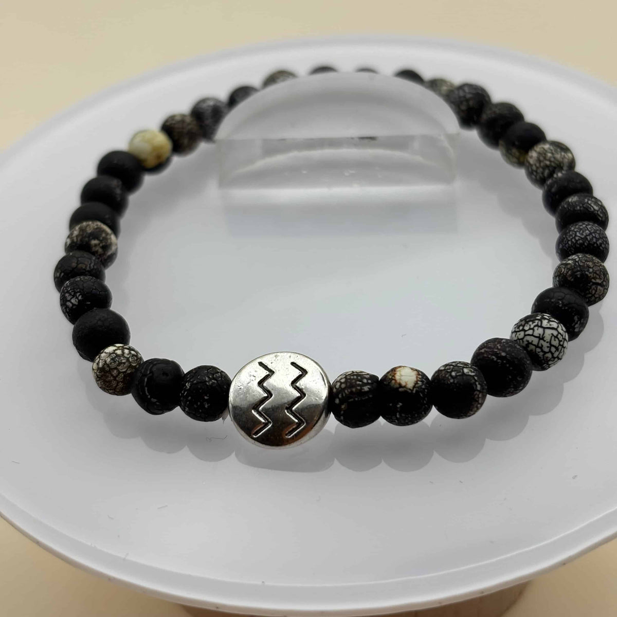 Un beau bracelet en perles sur élastique avec perles en porcelaine et en verre et médaillon avec le signe du verseau