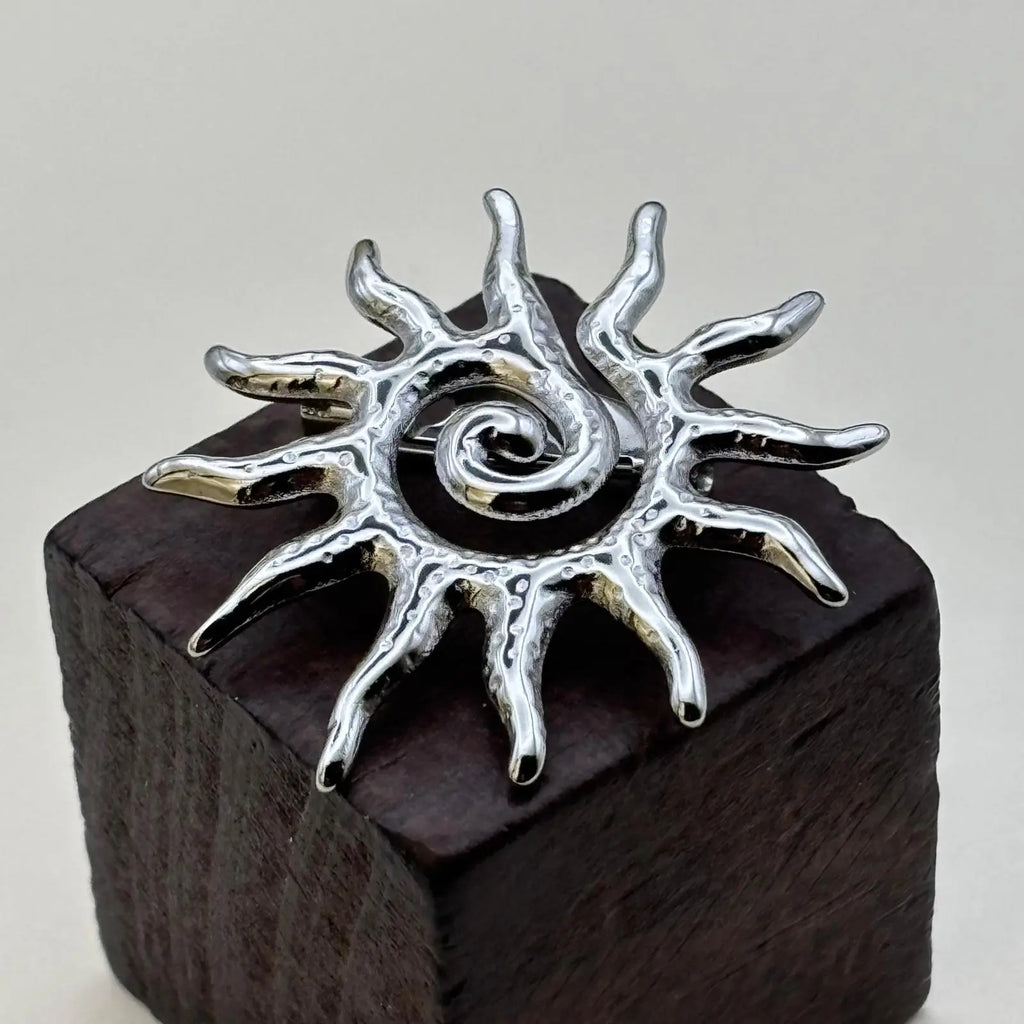 Broche argentée en forme de soleil 