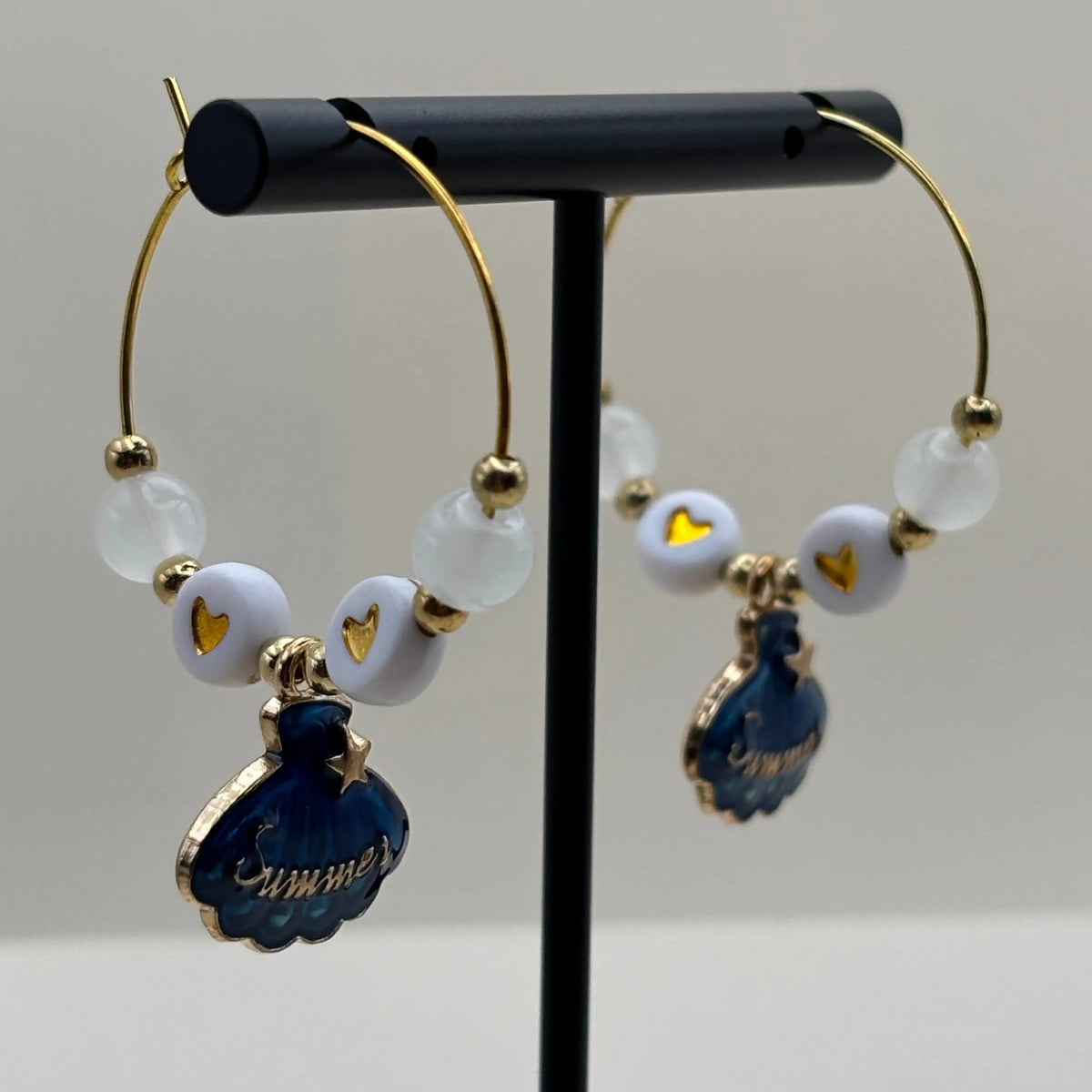 Des boucles d'oreilles créole avec breloque coquillage bleu et mot soleil 