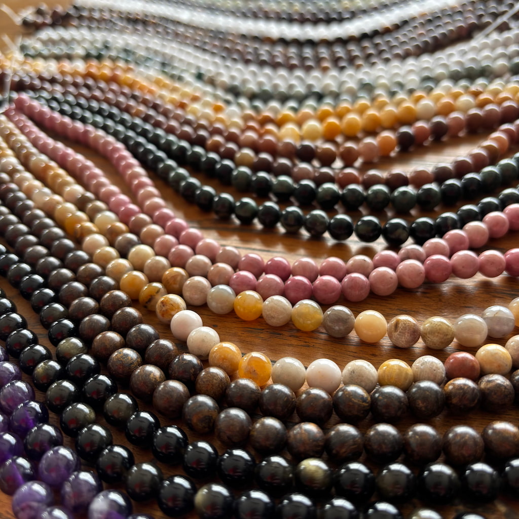 Des chapelets de différentes perles en pierres naturelles posés sur une table