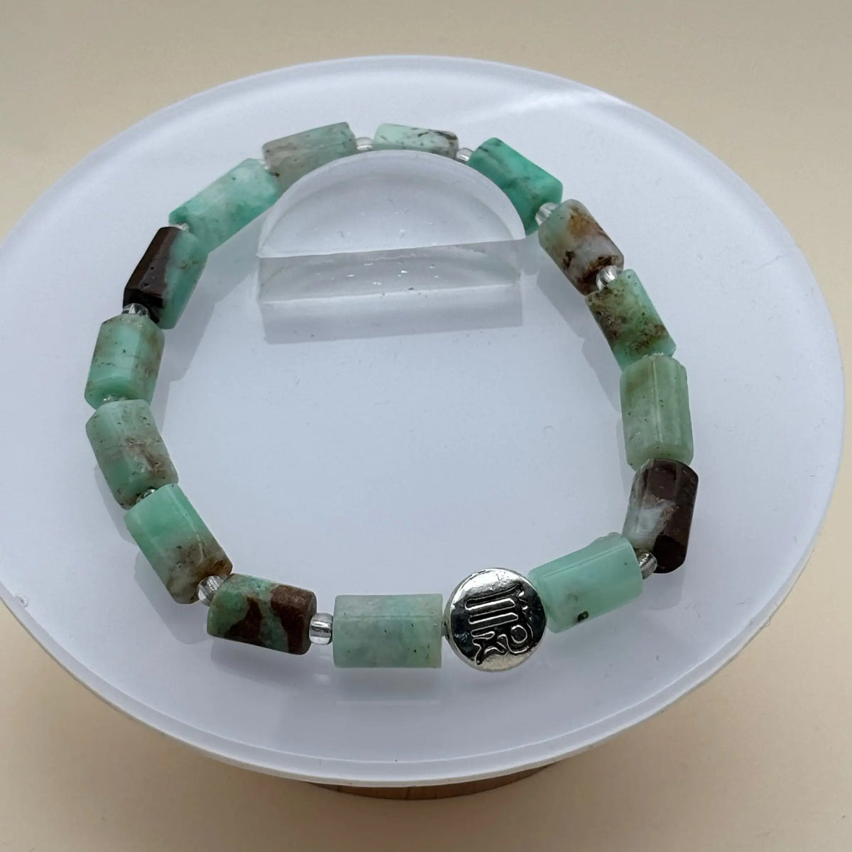 Bracelet aux perles rondes multicolores avec un médaillon argenté gravé placé à l’avant