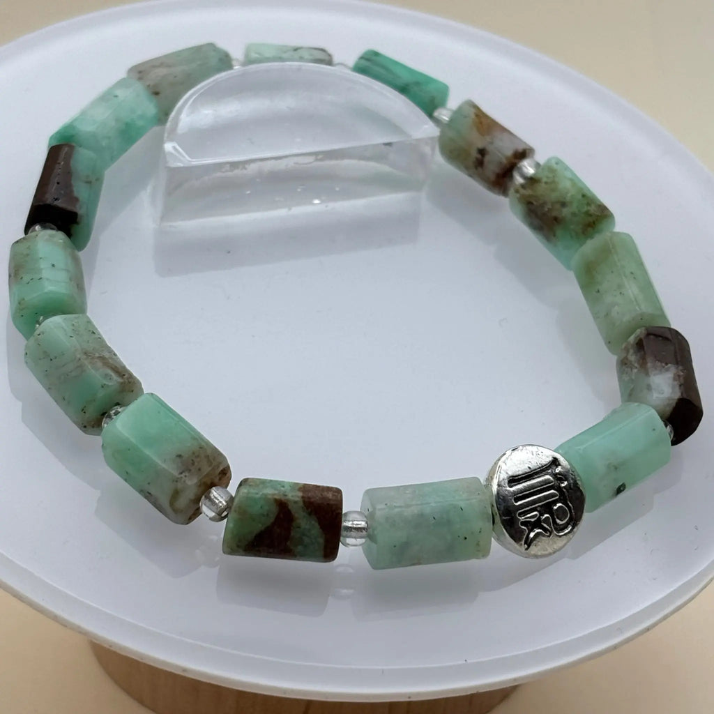 Bracelet composé de perles cylindriques vert pâle et brun, rehaussé d’un médaillon argenté gravé