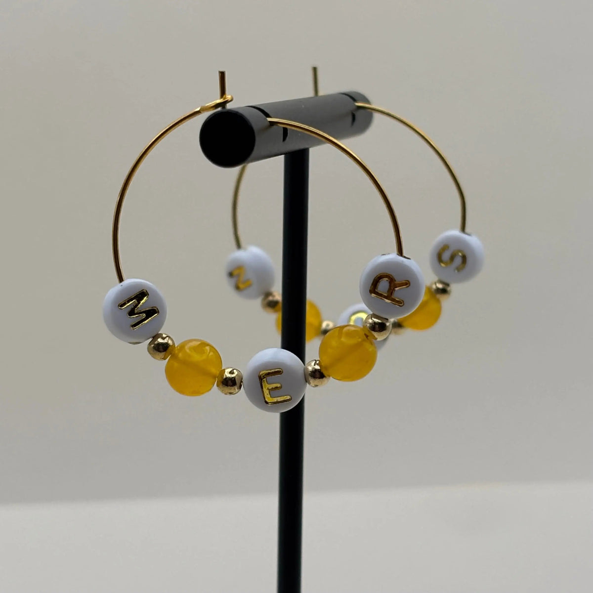 Des boucles d'oreilles créoles dorées avec le mot mer sur des perles et des perles oranges 