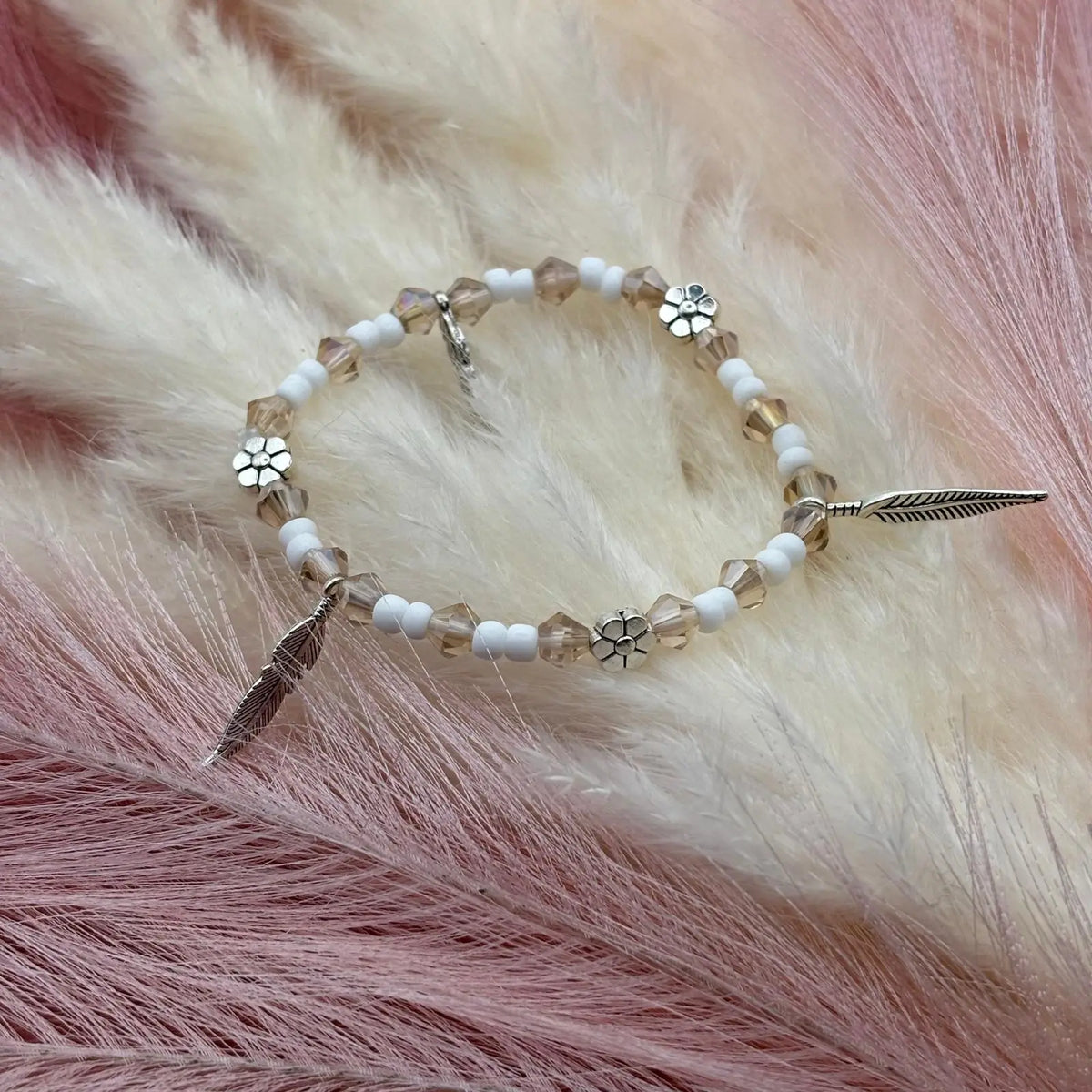 Bracelet en perles artisanal avec breloques plumes et fleurs et perles en verre blanche sur élastique