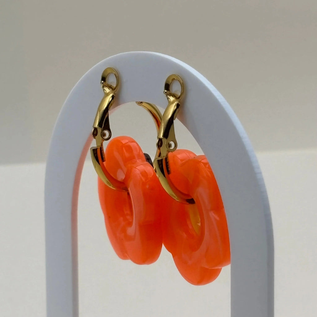 Une paire de petites boucles d'oreilles créoles dorées avec fleur couleur orange