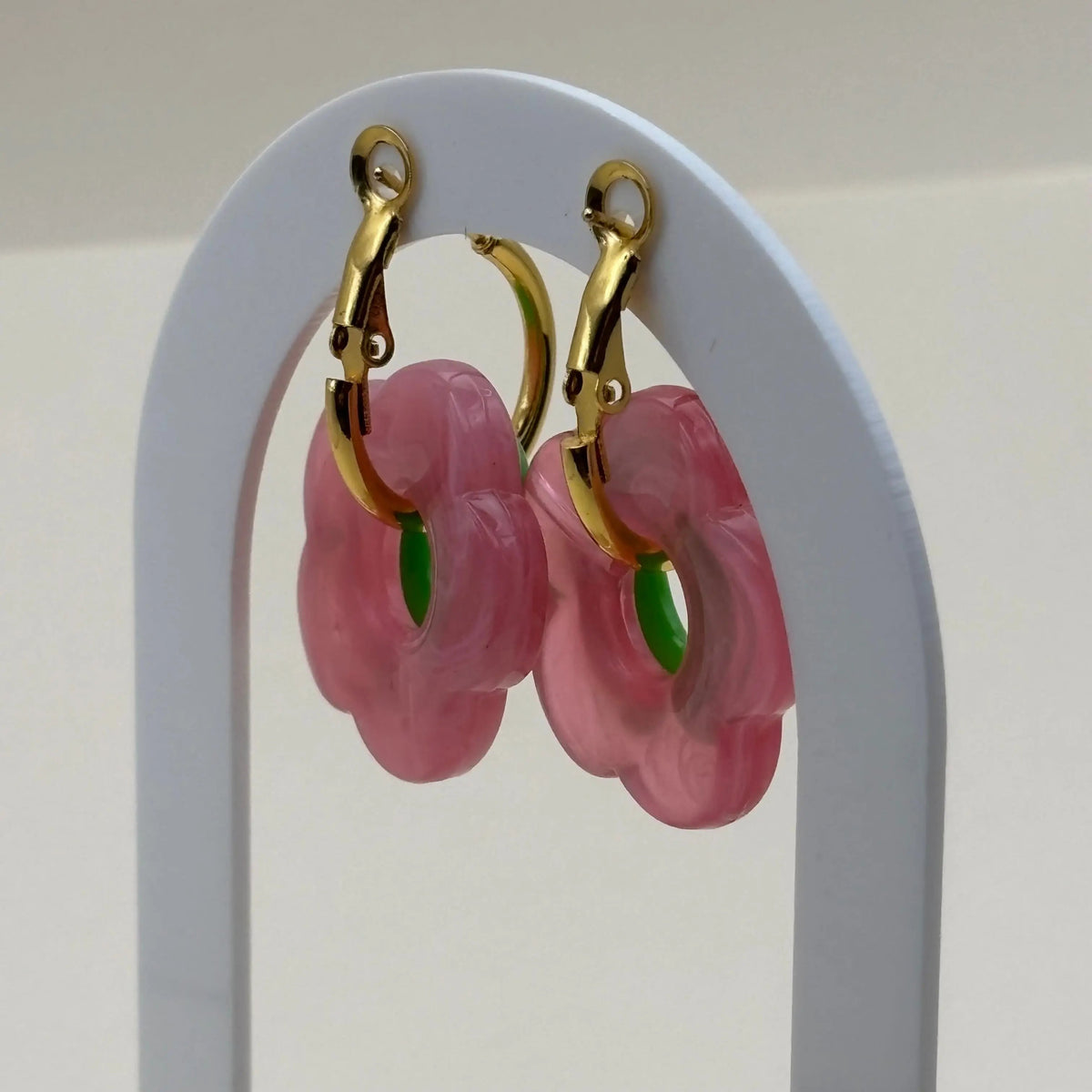 Une paire de petites boucles d'oreilles créoles dorées avec fleur verte