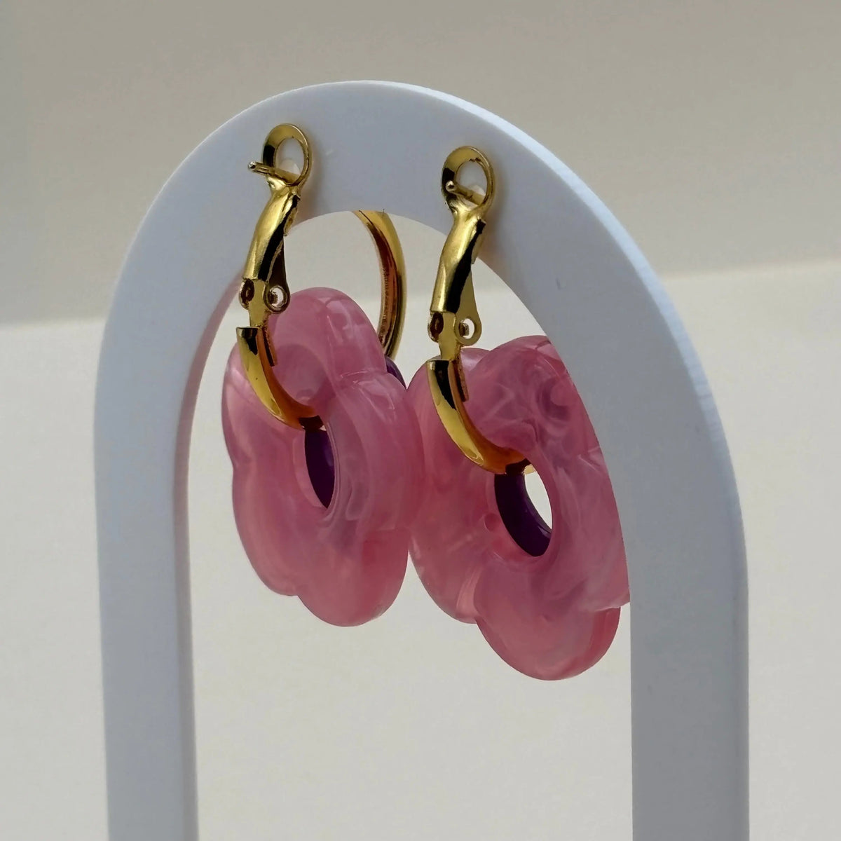 Une paire de petites boucles d'oreilles créoles dorées avec fleur violette