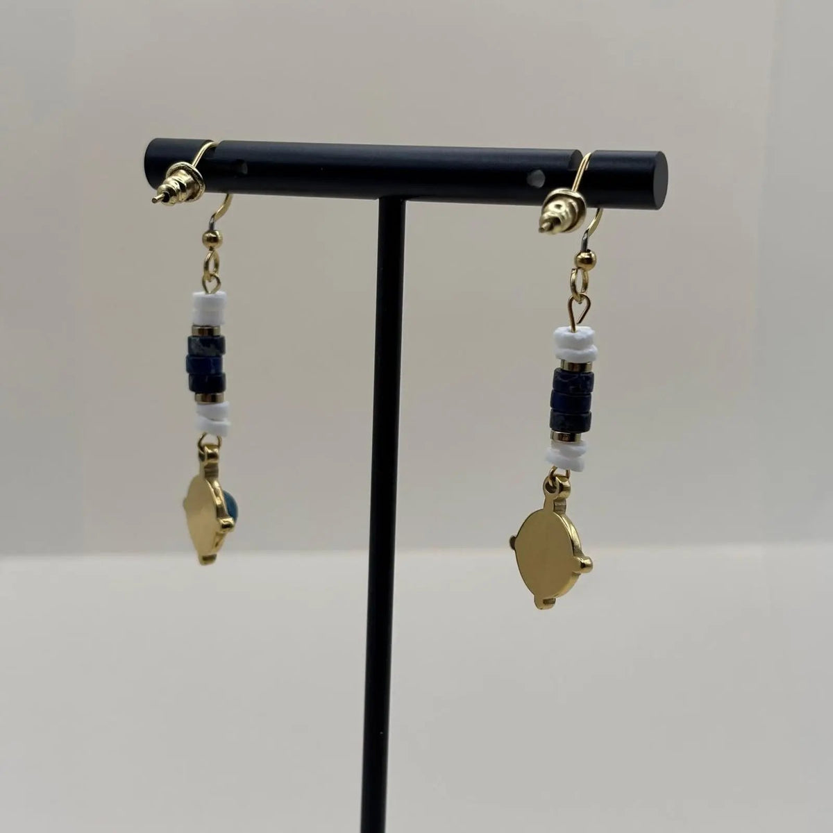 Des boucles d'oreilles artisanales avec attache dorée et breloque bleue et dorée en forme de cercle