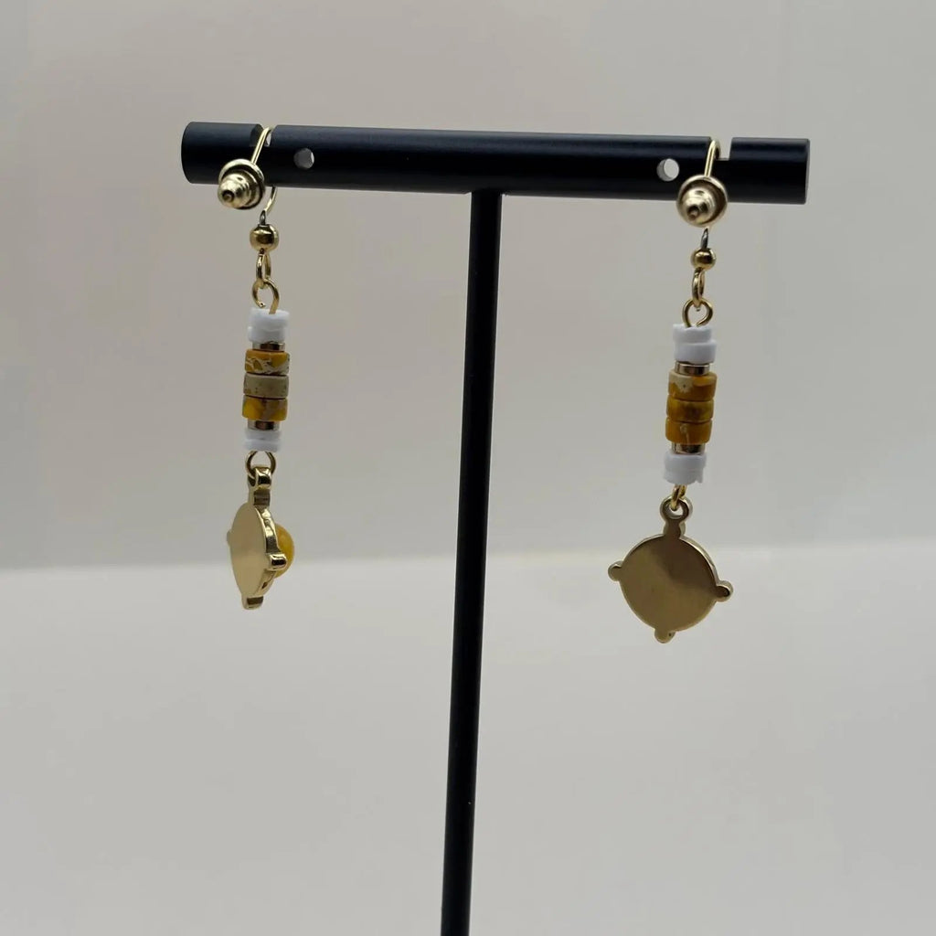 Des boucles d'oreilles artisanales avec attache dorée et breloque jaune et dorée en forme de cercle