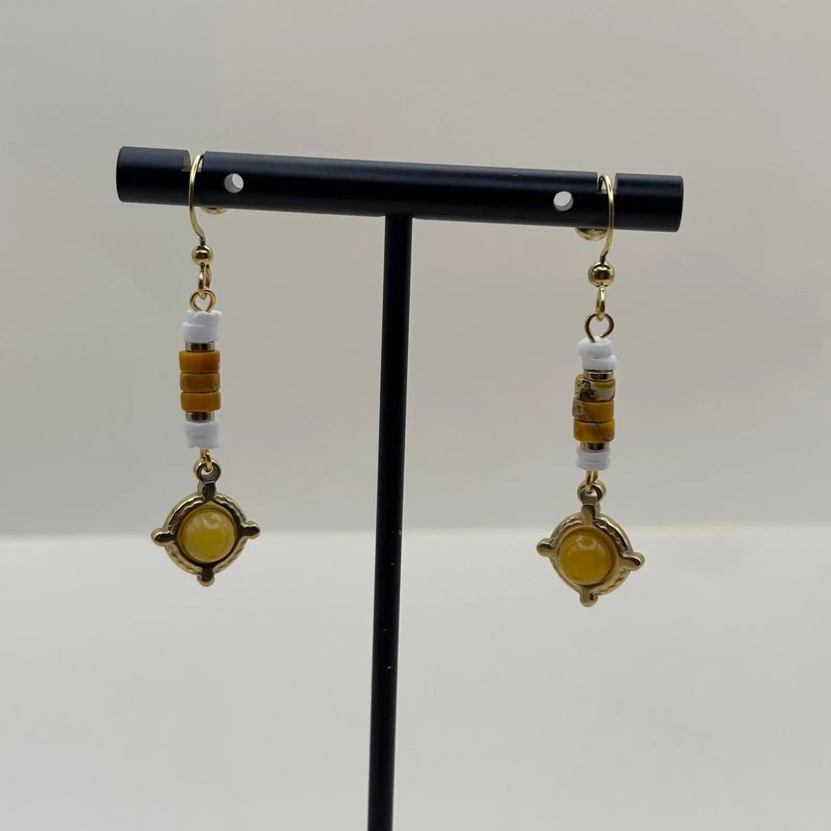 Des oucles d'oreilles artisanales avec attache dorée et breloque jaune et de couleur dorée en forme de cercle