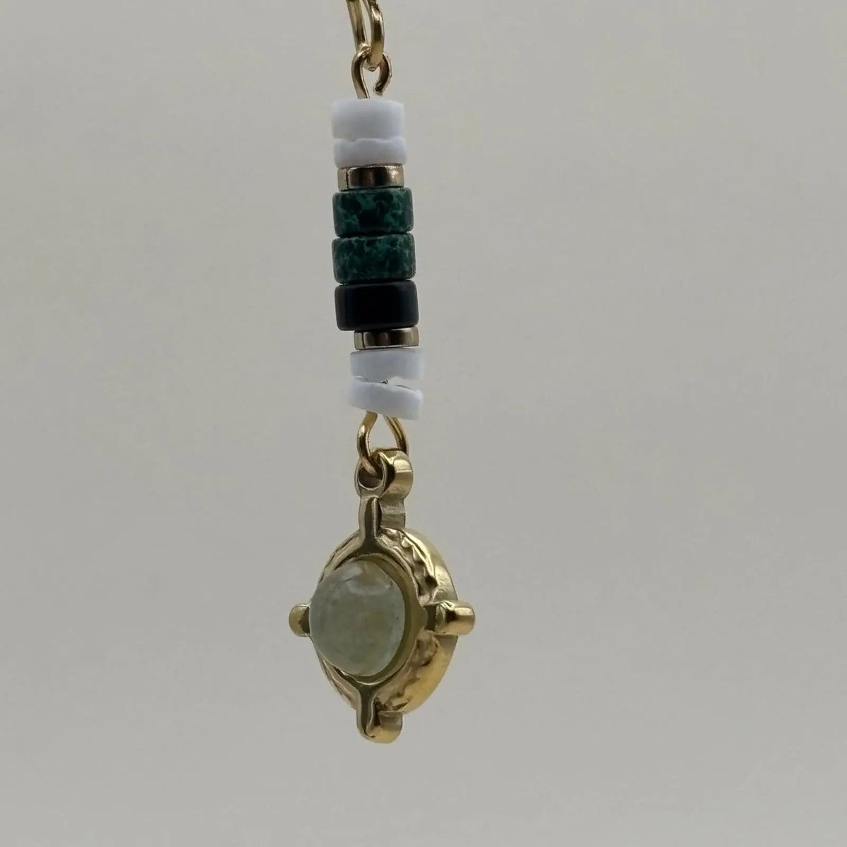 Des boucles d'oreilles artisanales avec attache dorée et breloque verte et dorée en forme de cercle