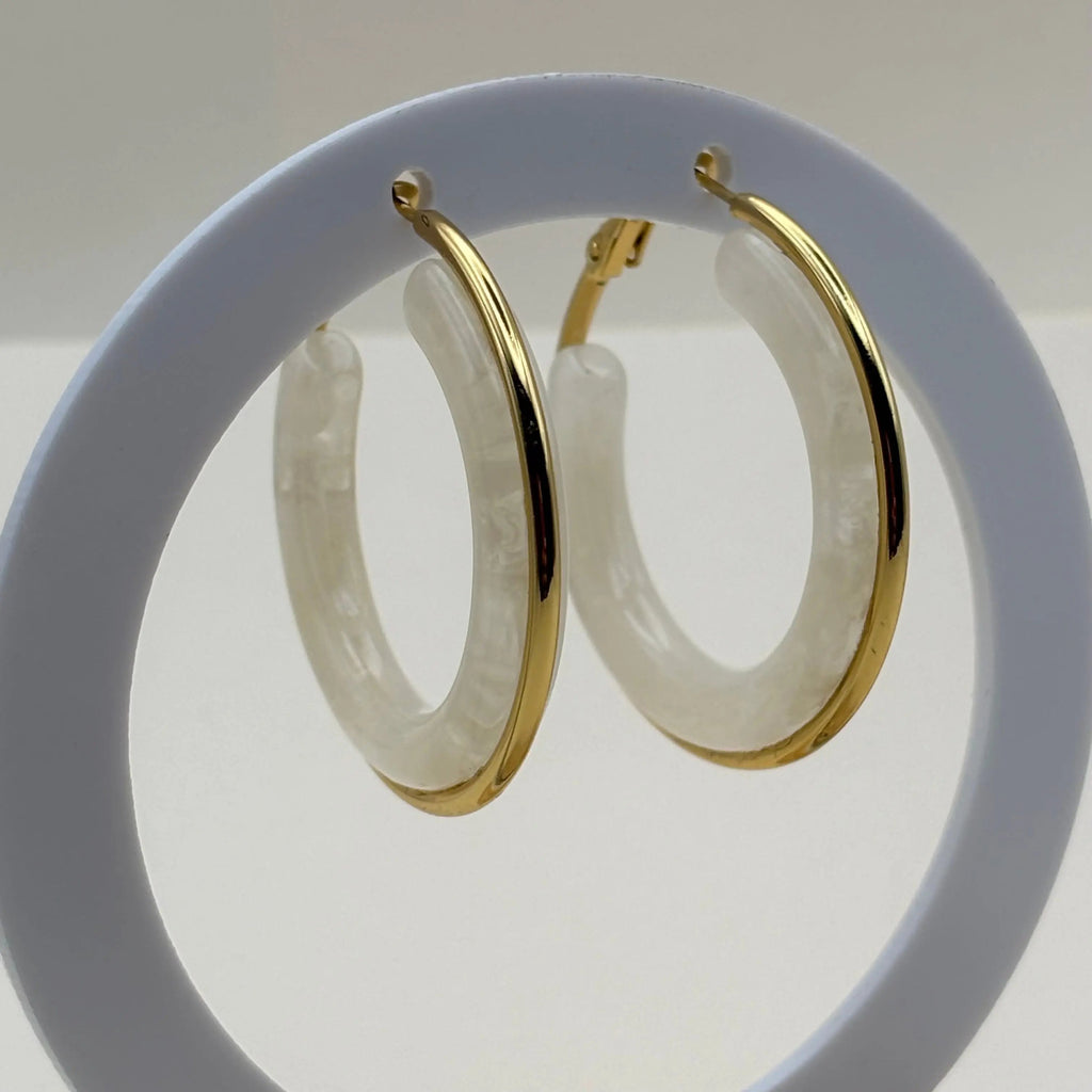 Des boucles d'oreilles créoles dorées avec insert d'un anneau blanc 