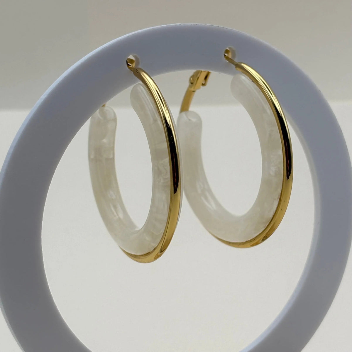 Des boucles d'oreilles créoles dorées avec insert d'un anneau blanc 