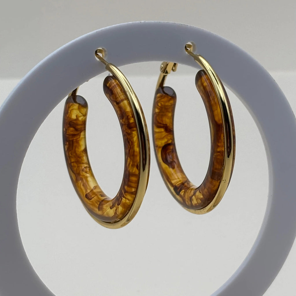 Des boucles d'oreilles créoles dorées avec insert d'un anneau marron