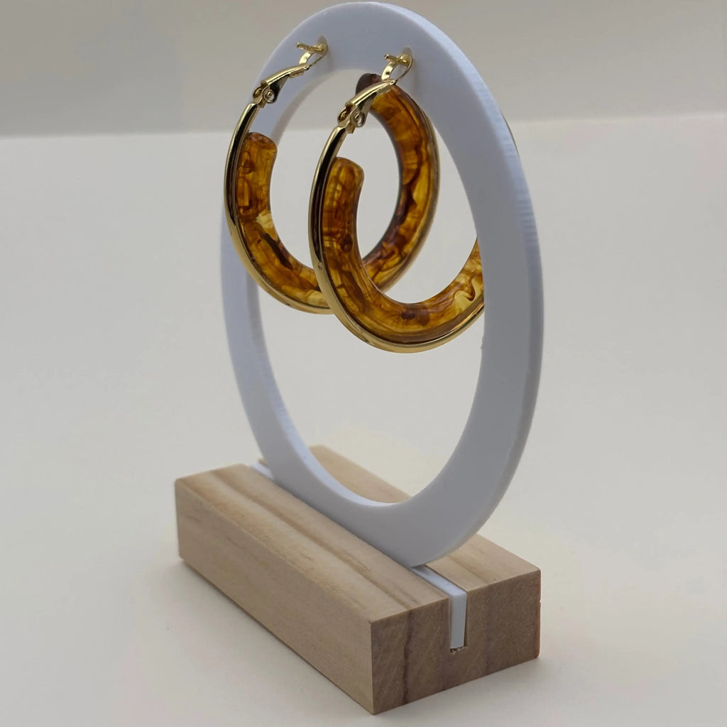 Une paire de boucles d'oreilles créoles dorées avec insert d'un anneau marron