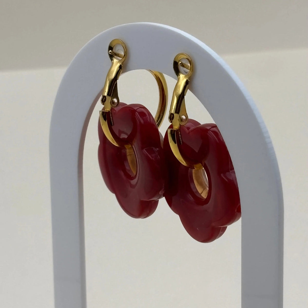 Une paire de petites boucles d'oreilles créoles dorées avec fleurs rouges