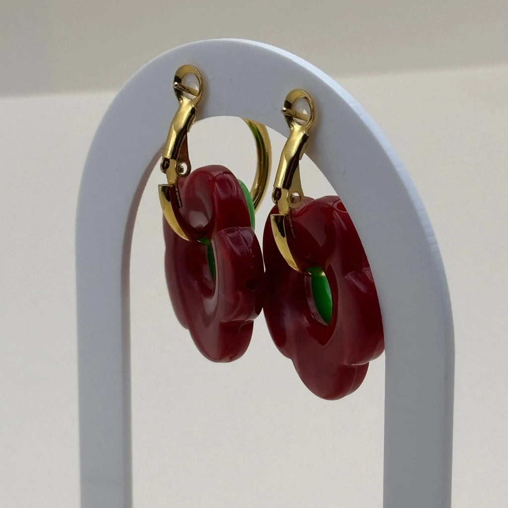 Une paire de petites boucles d'oreilles créoles dorées avec fleur rouge et verte