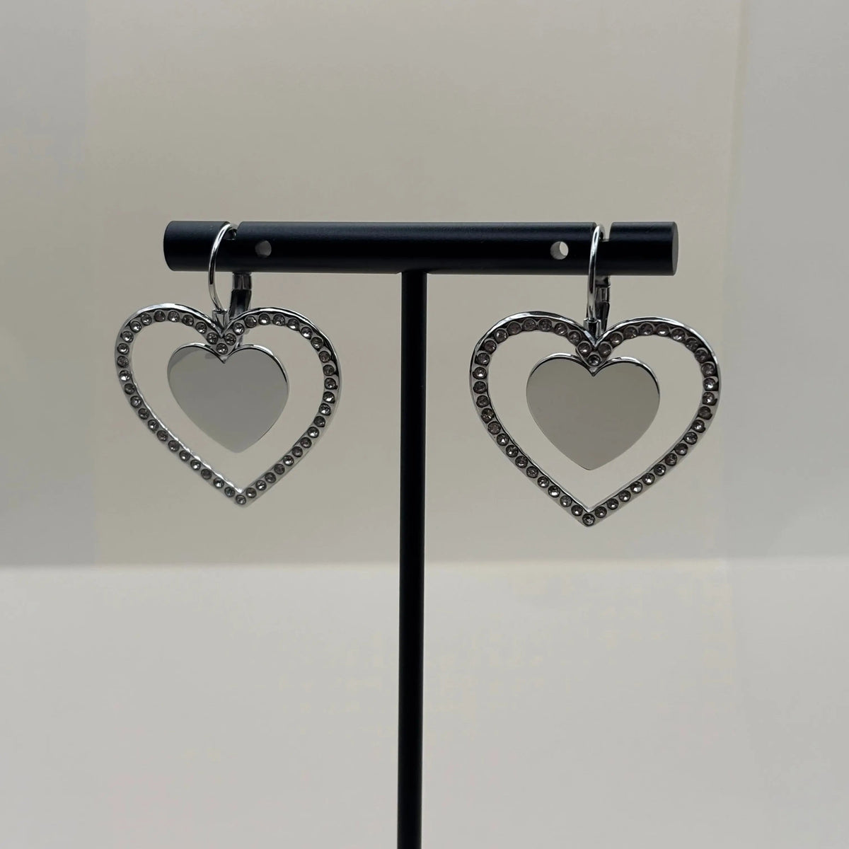 Des boucles d'oreilles argentées avec motif double cœur entouré de strass en acier inoxydable
