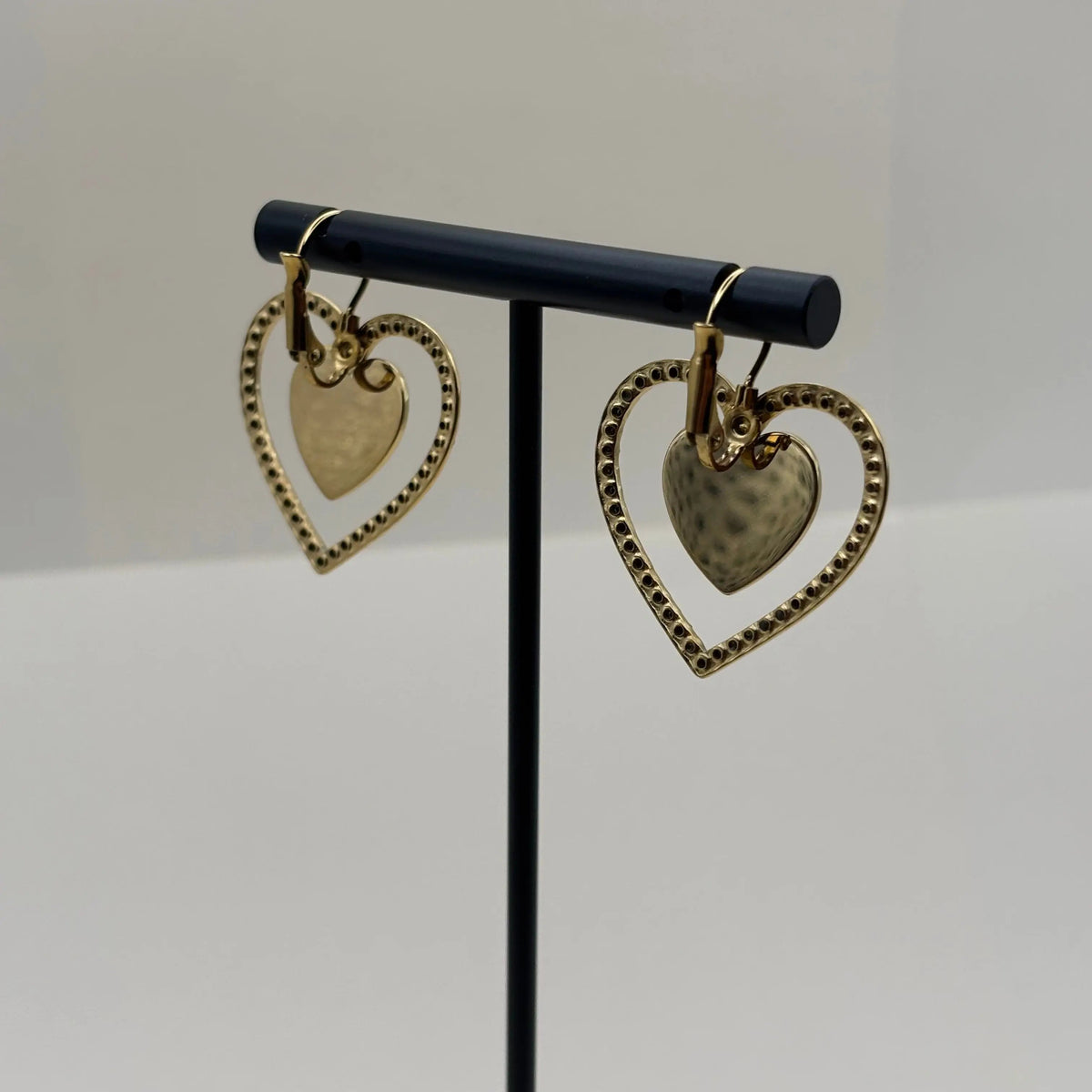 Des boucles d'oreilles dorées avec motif double cœur entouré de strass en acier inoxydable