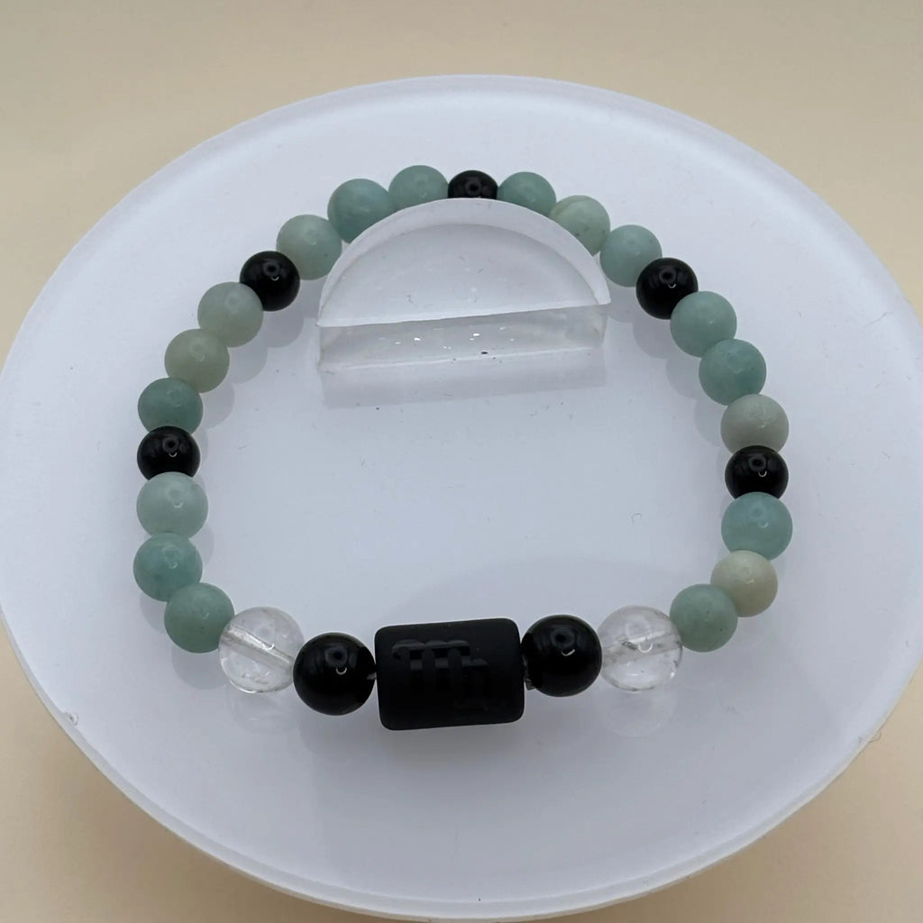 Bracelet composé de perles vert clair, noires et transparentes avec un cylindre noir gravé en élément central