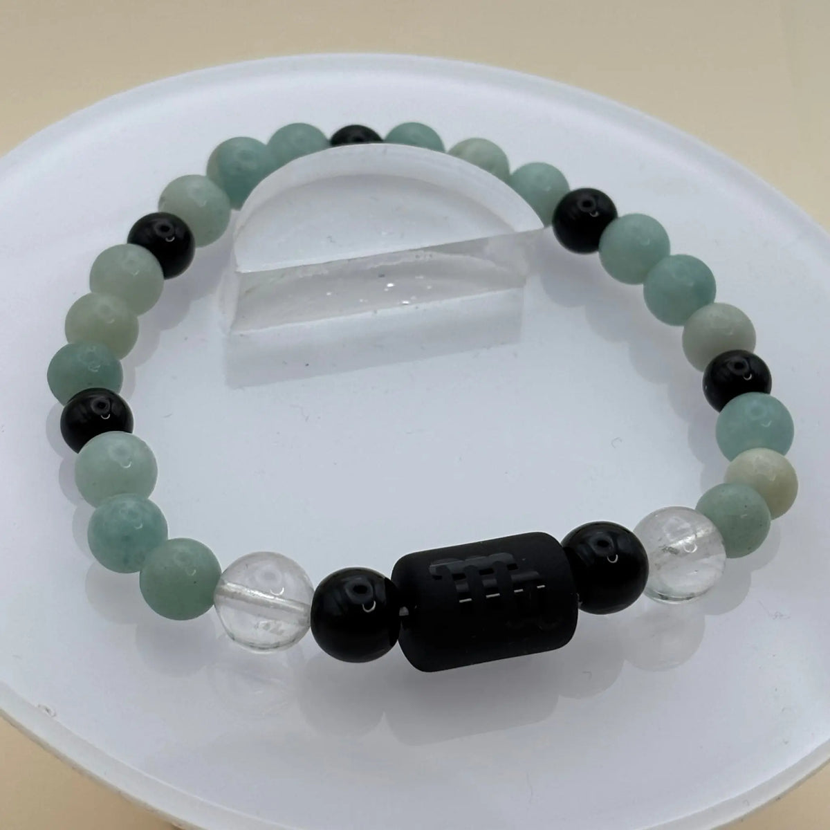 Bracelet associant perles vert clair, noires et transparentes avec un élément central noir gravé