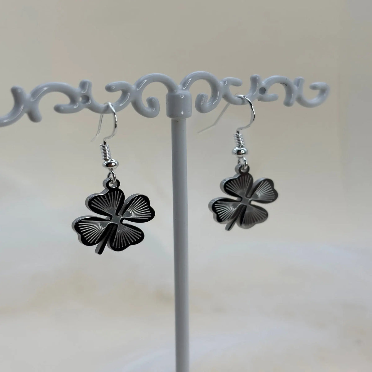 Une paire de boucles d'oreilles argentées avec un trèfle à quatre feuilles