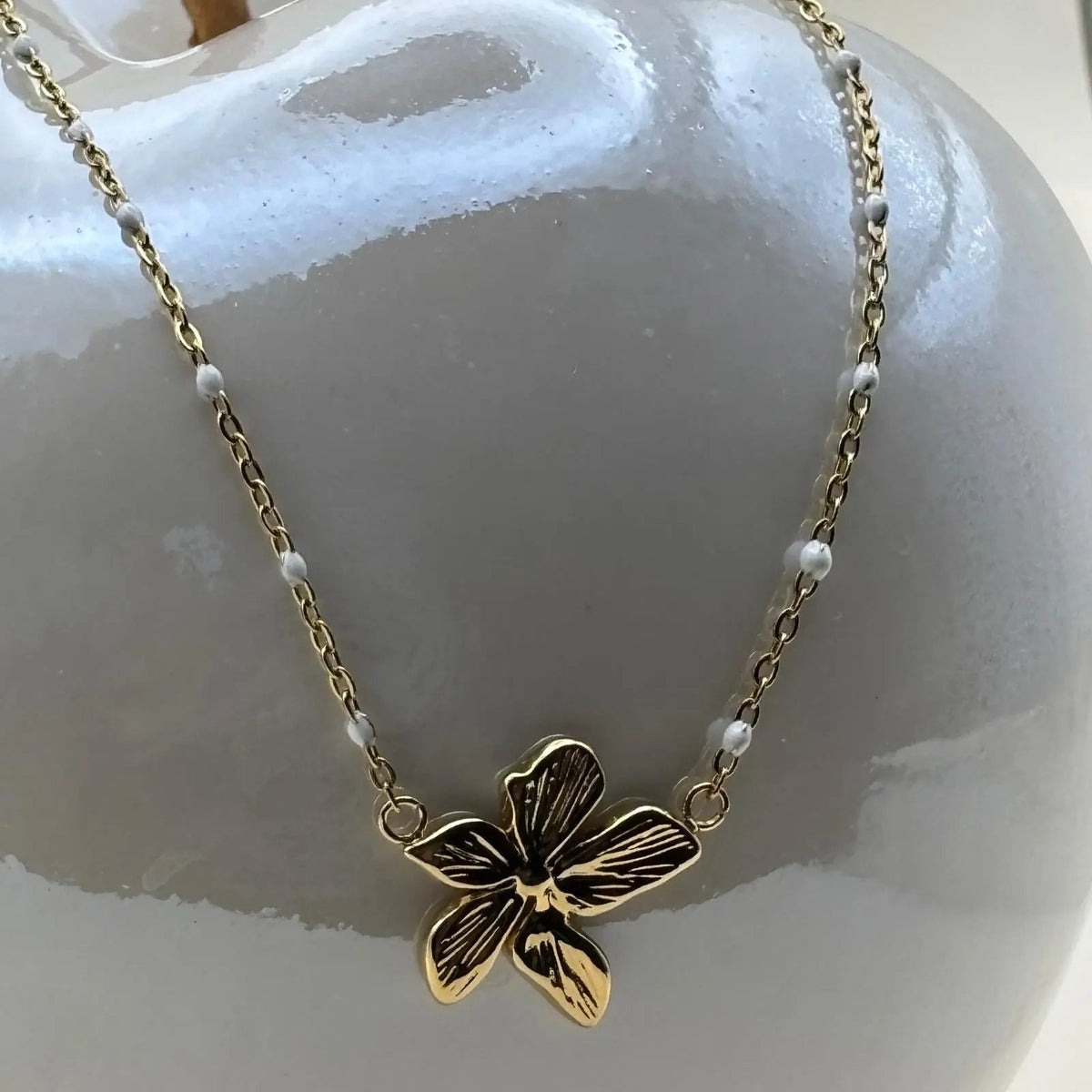 Collier avec des petits maillons dorés et pendentif central avec une fleur dorée