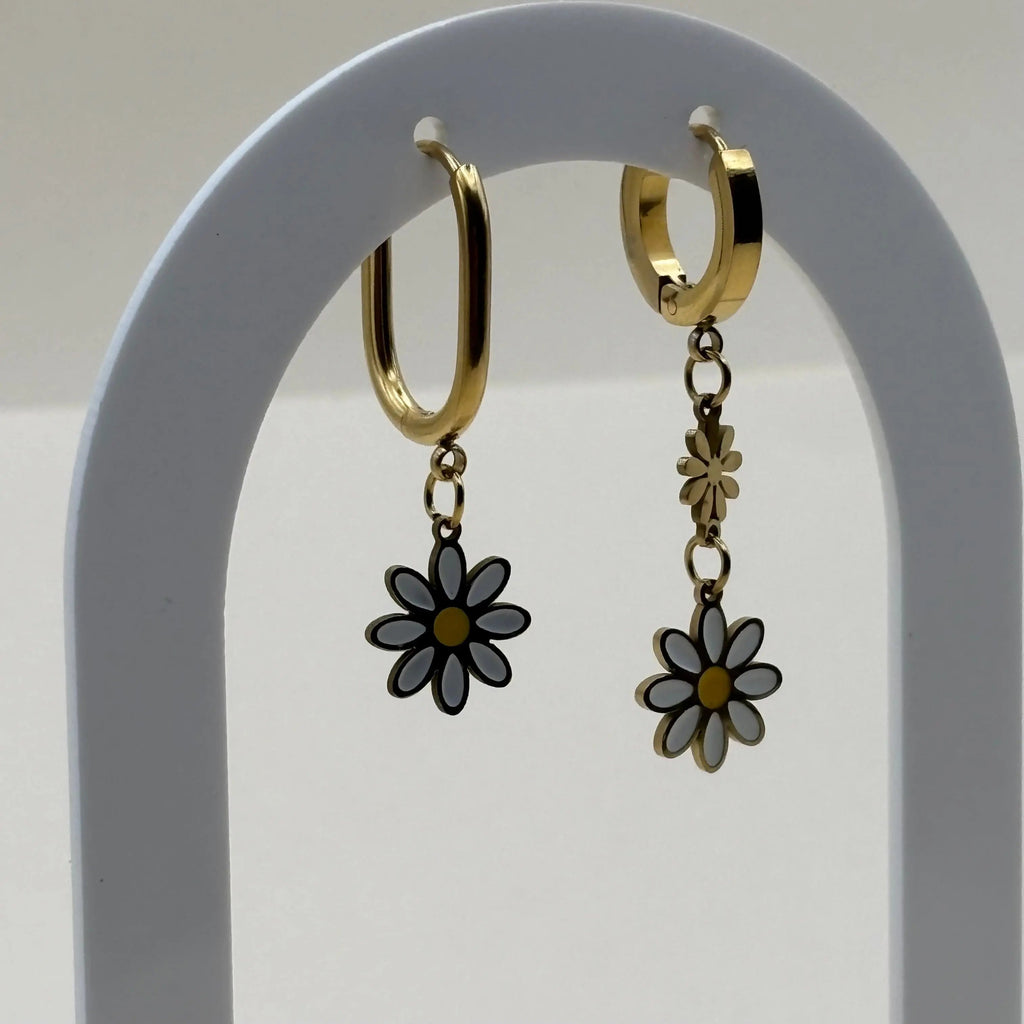 Des petites boucles d'oreilles asymétriques créoles avec des marguerites blanches et orange