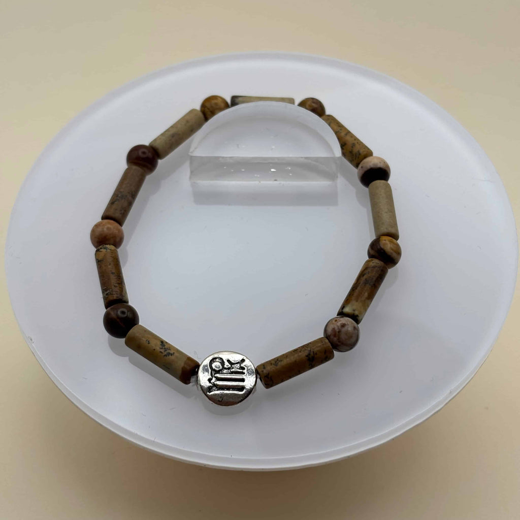 Un bracelet en perles sur élastique avec perles en porcelaine et en verre et médaillon avec le signe zodiacal de la vierge