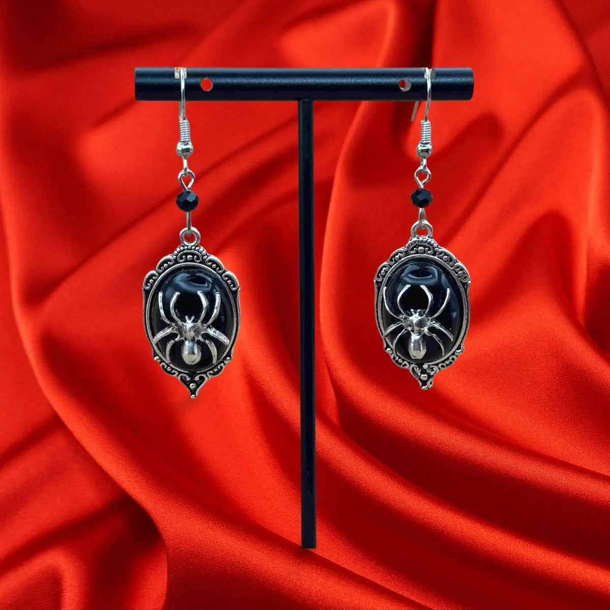 Boucles d'oreilles pendentif halloween en forme de médaillon argentée et fond noir et une grosse araignée dessus vendues sur le site pretes a briller