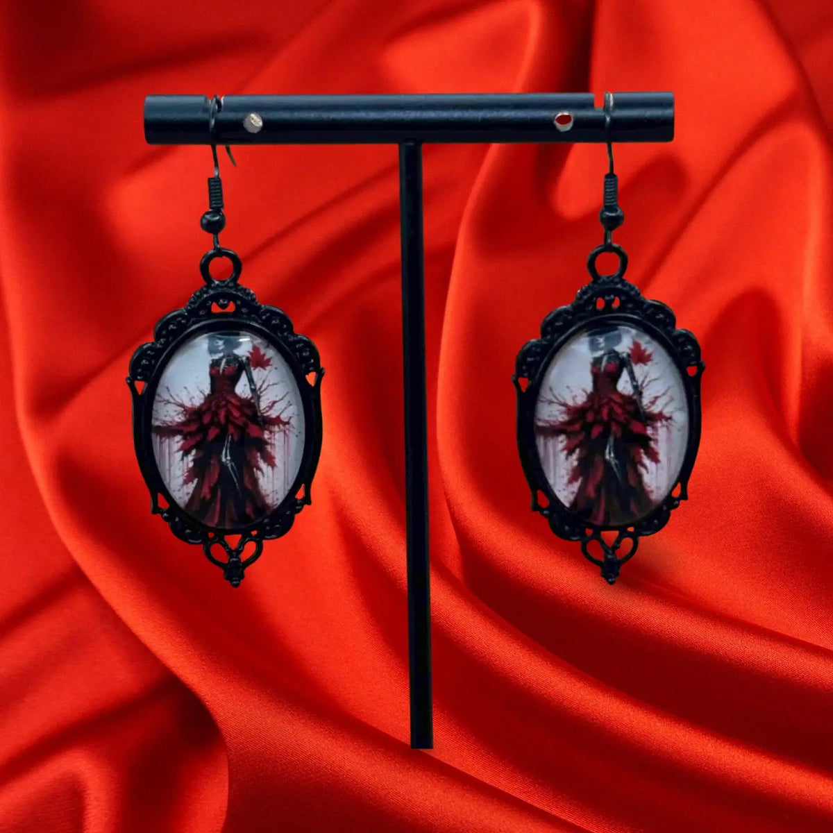 Boucles d'oreilles halloween en forme de médaillon noir avec à l'intérieur une femme en robe noire ornée de plumes rouges vendues sur le site pretes a briller