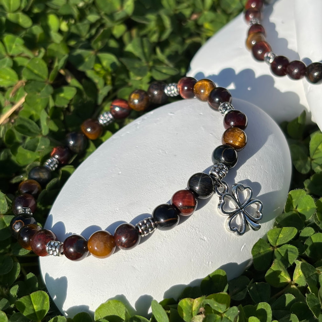 Vue de près d'un ensemble de deux bracelets artisanaux en perles oeil de tigre marbré et une breloque en forme de trèfle argenté