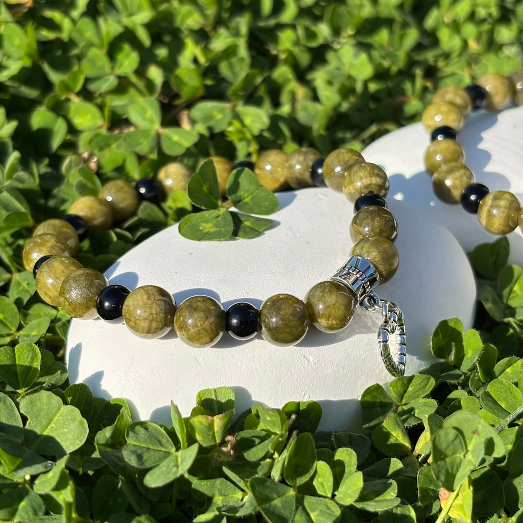 Vue de près d'un ensemble de deux bracelets artisanaux en perles de jaspe et obsidienne et une breloque en forme de coeur argenté