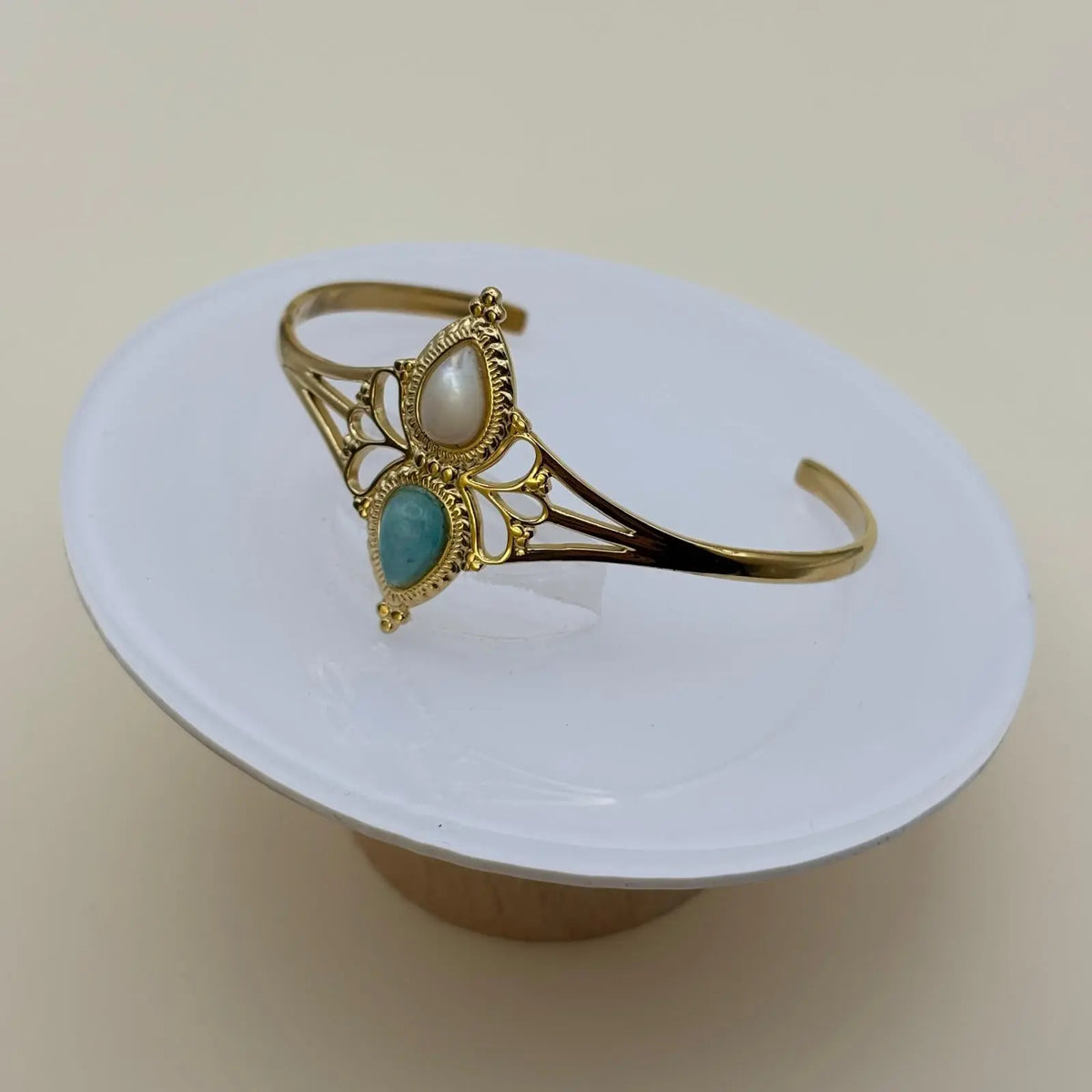 Bracelet de couleur dorée rigide ouvert en acier inoxydable avec deux pierres blanche et turquoise