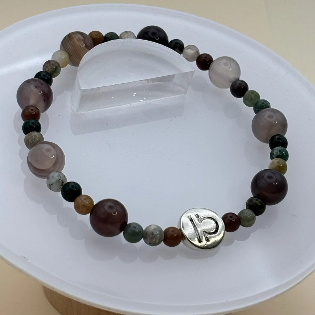 Bracelet aux perles rondes multicolores avec un médaillon argenté gravé placé à l’avant