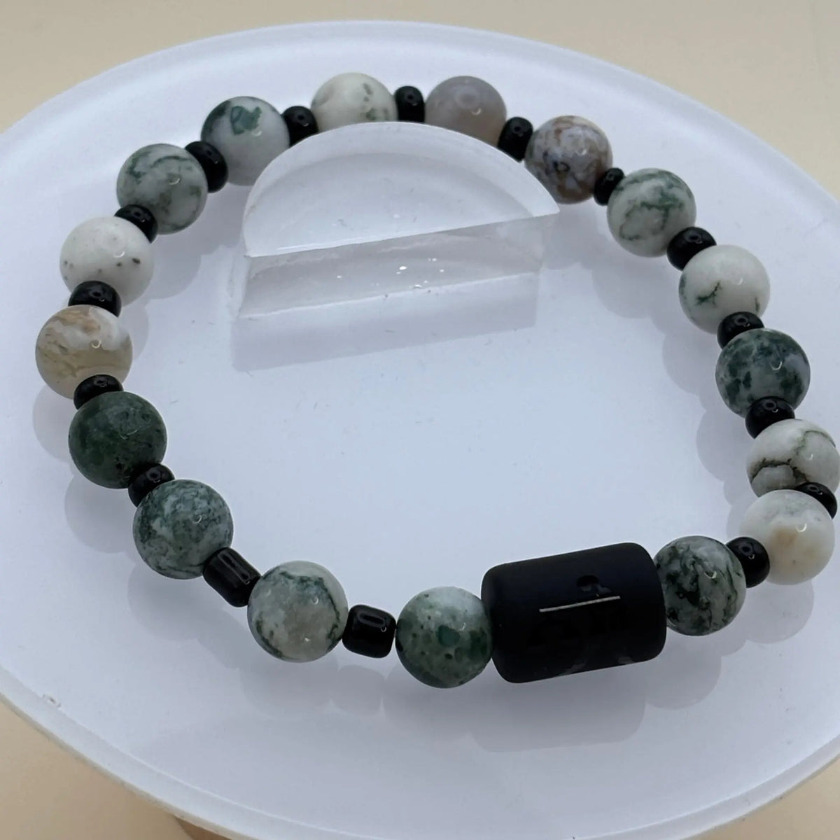 Bracelet aux perles rondes blanches et vert foncé avec un cylindre noir gravé comme pièce centrale