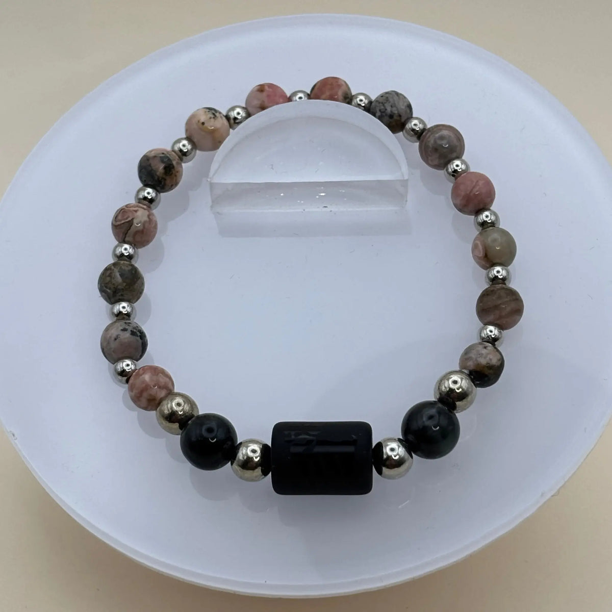 Bracelet alternant perles rosées marbrées et perles argentées avec un cylindre noir gravé