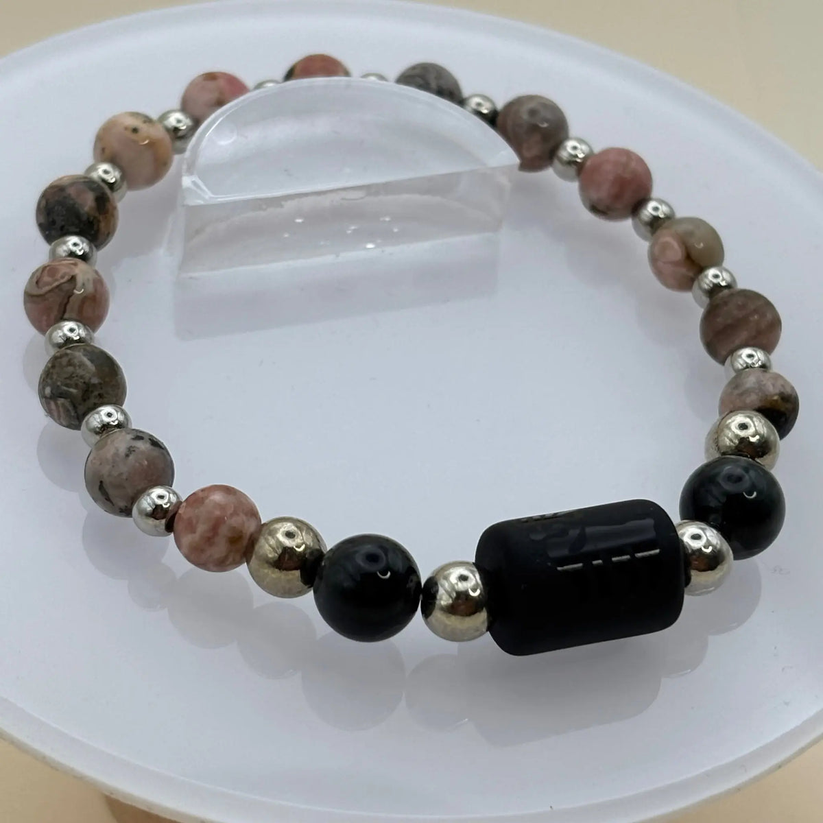 Bracelet aux perles roses et gris clair accompagnées de billes argentées et d’un cylindre noir gravé