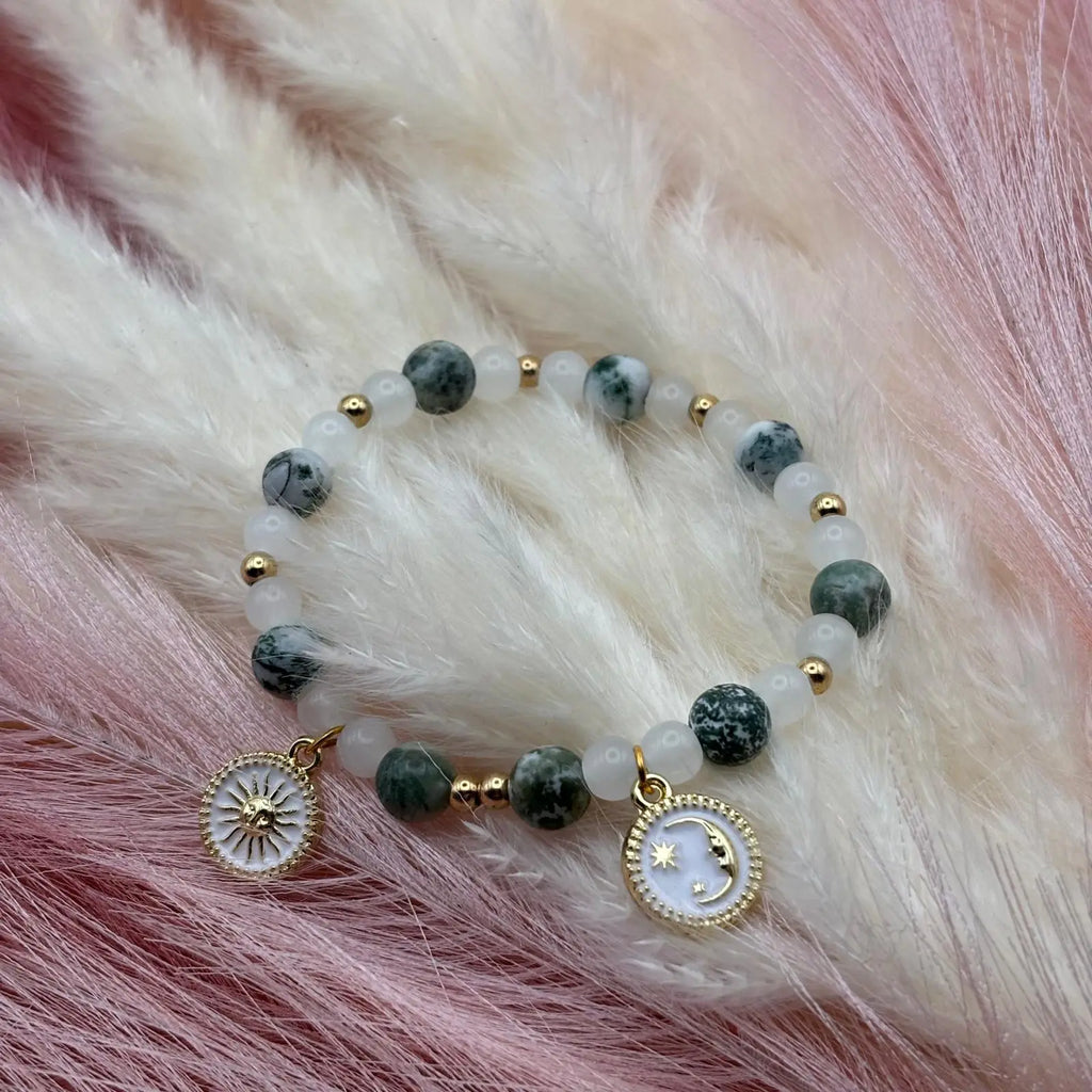 Vue de près d'un bracelet en perles artisanal avec breloques lune et soleil et perles naturelles marbrées verte sur élastique vendu 