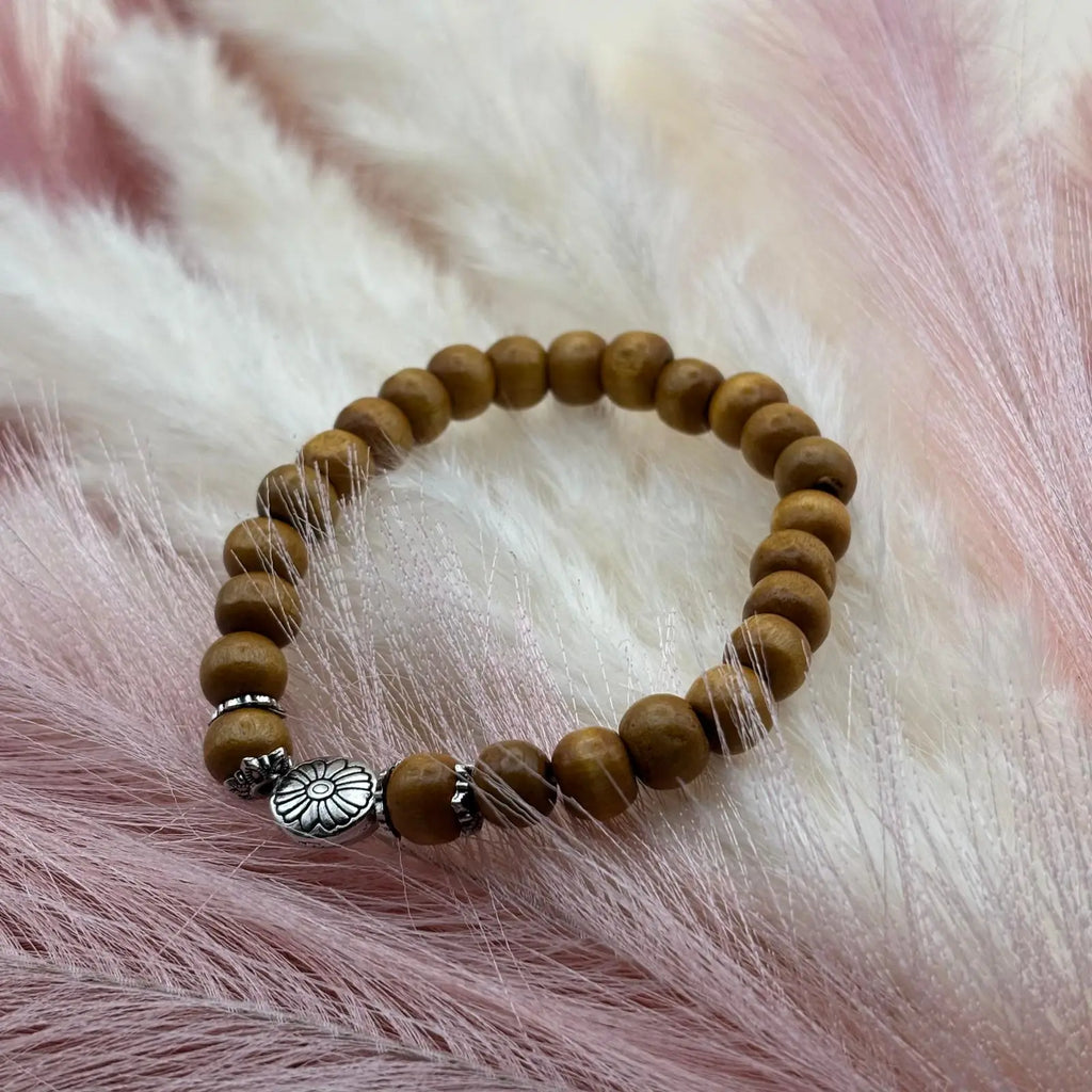 Bracelet en perles artisanal avec une breloque en forme de fleur argentée et des perles en bois