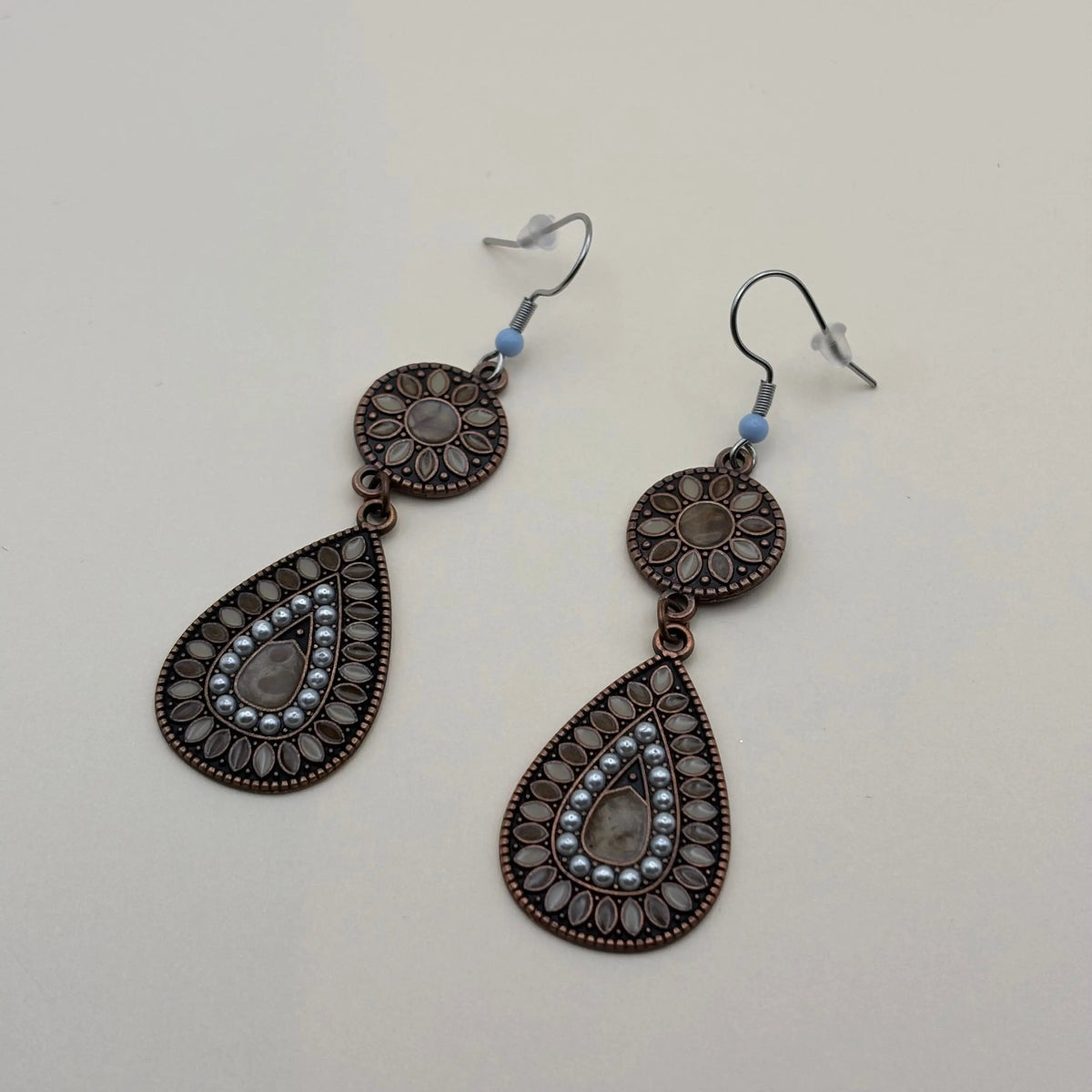 Une paire de boucles d'oreilles attache argentée avec motifs de fleurs rondes et allongées et touche de peinture