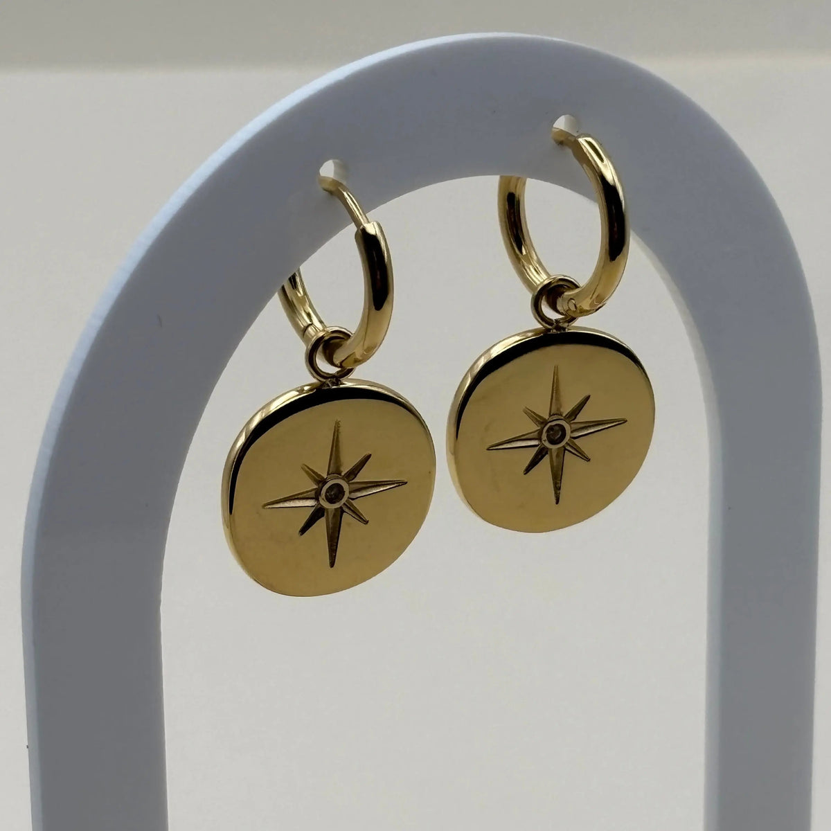 Des Mini créole et pendentif avec pastille dorée gravée d'une rose des vents en acier inoxydable