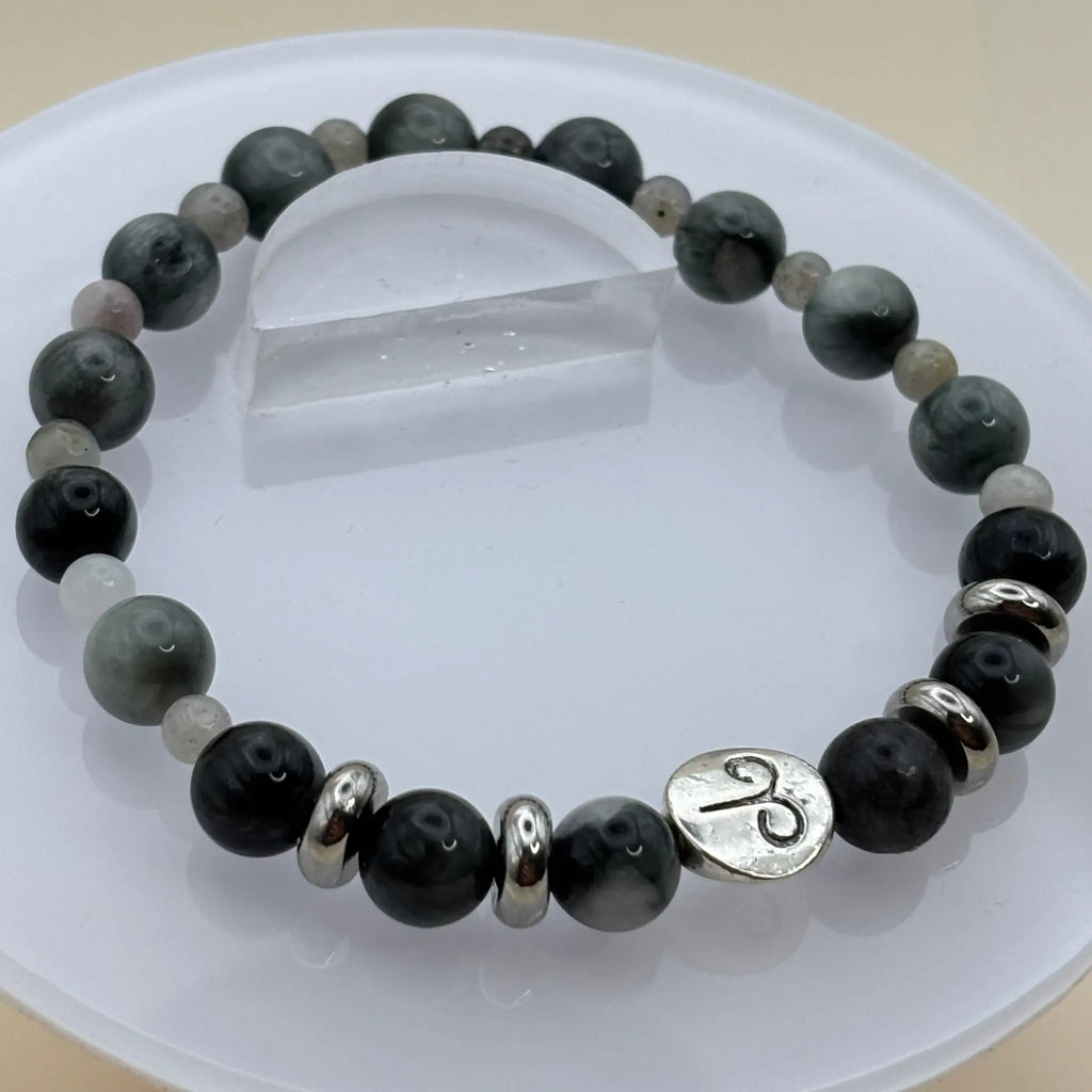 Bracelet composé de perles gris foncé et anneaux argentés décoré d’un médaillon argenté gravé