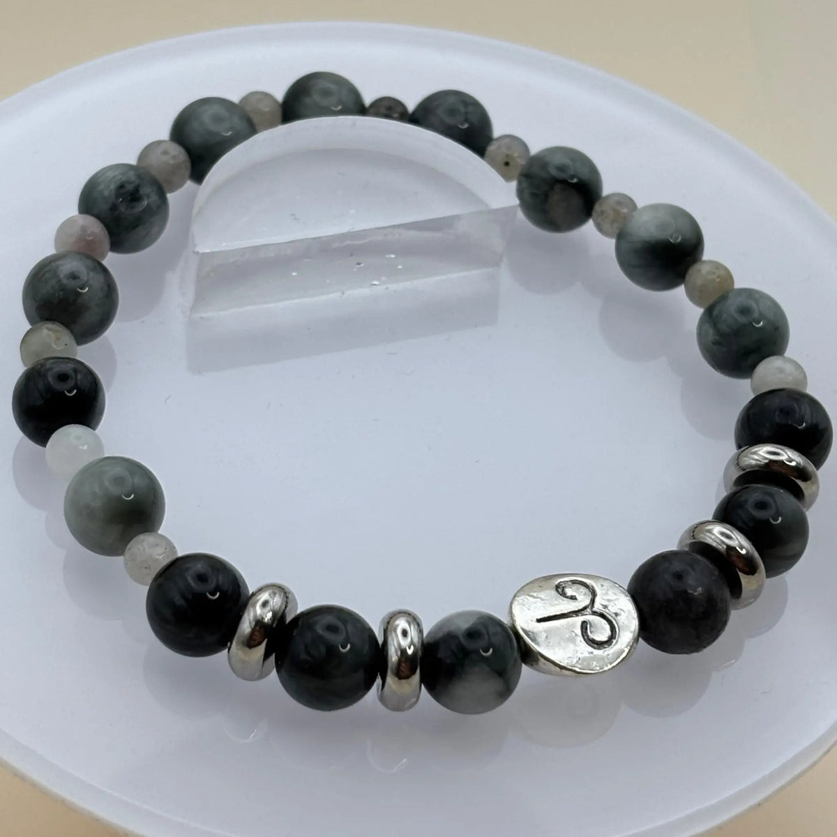 Bracelet composé de perles gris foncé et anneaux argentés décoré d’un médaillon argenté gravé