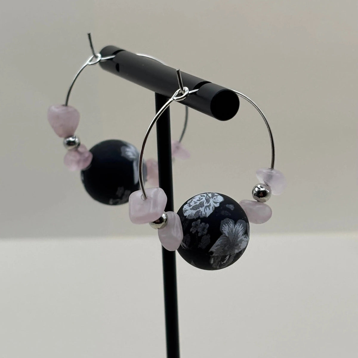 Une paire de boucles d'oreilles créoles avec pendentifs marbrés et pierres roses 