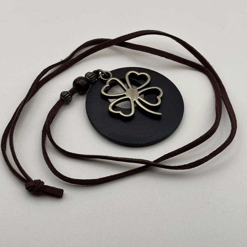 Un collier fantaisie en médaillon en bois marron motif porte bonheur trèfle et cordon en cuir