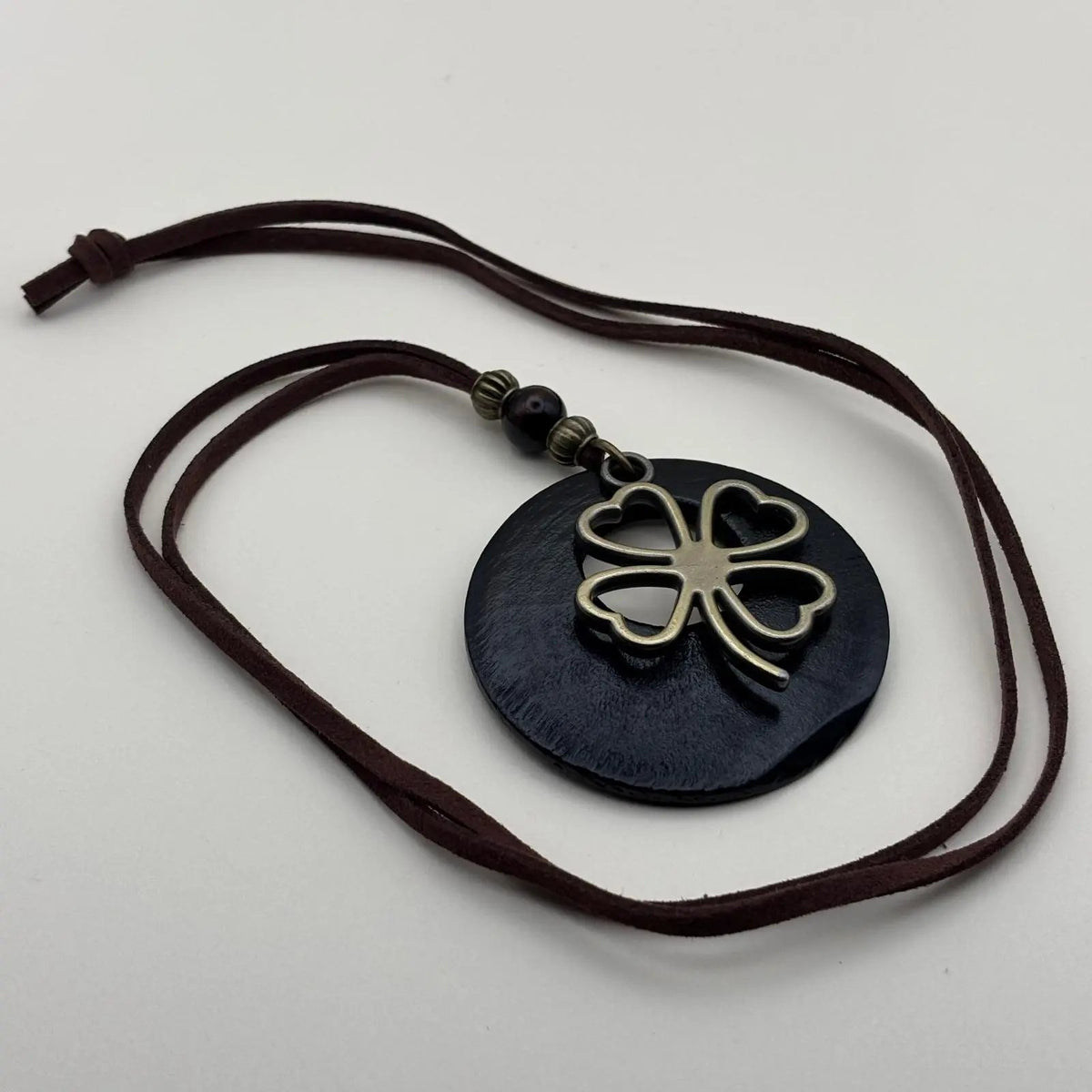 Collier fantaisie en médaillon en bois noir motif porte bonheur trèfle et cordon en cuir