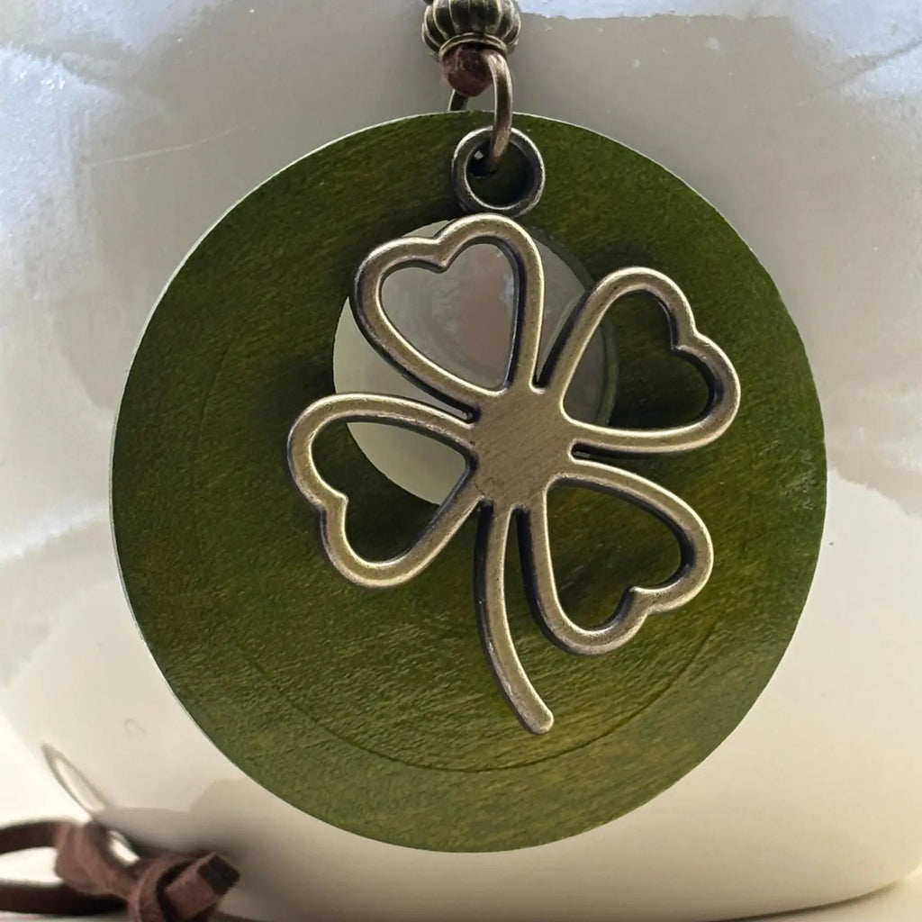 Un collier fantaisie en médaillon en bois vert motif porte bonheur trèfle et cordon en cuir